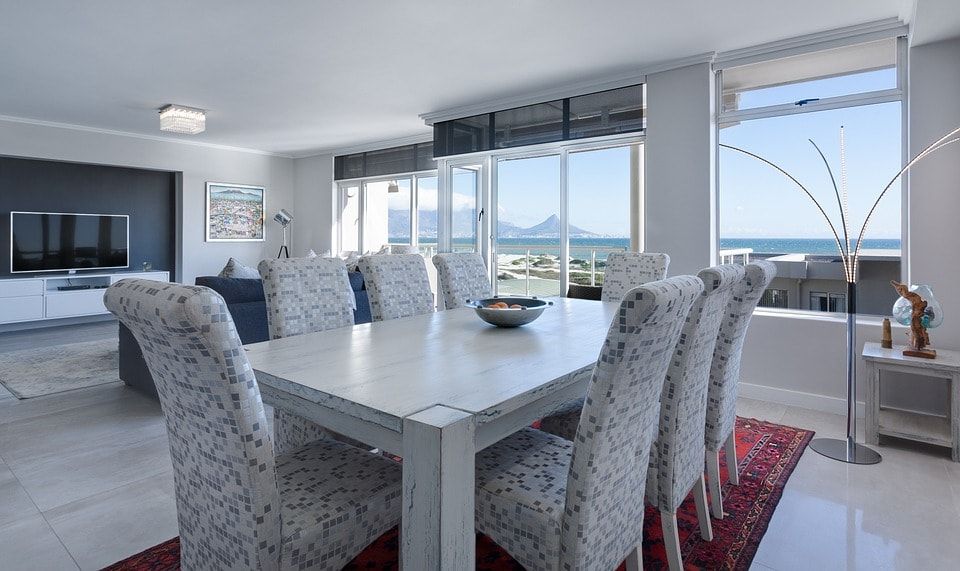 Salón decorado en tonos fríos con cristalera con vistas al mar y la montaña